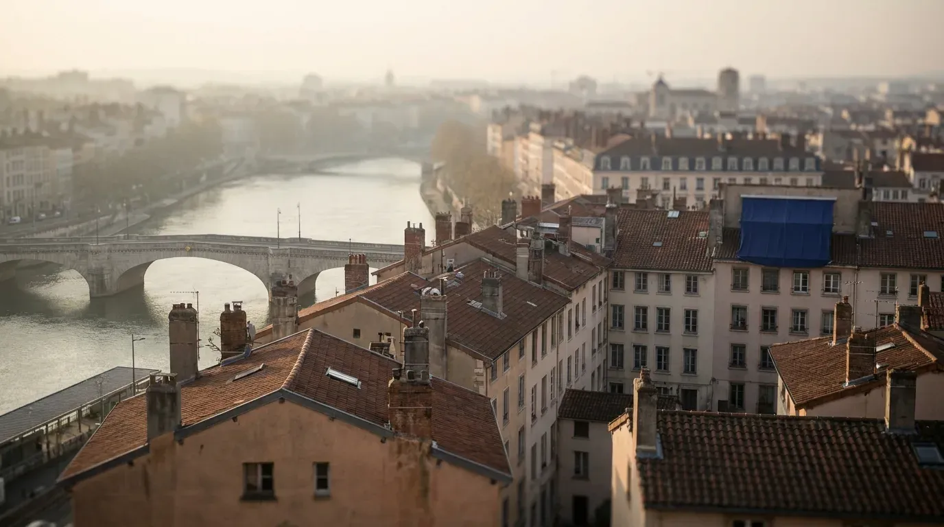 Toits en tuiles de Lyon vus d’en haut au petit matin, la Saône et un pont de pierre en contrebas dans la brume : le terrain sur lequel se comparent les devis des agences SEO lyonnaises.